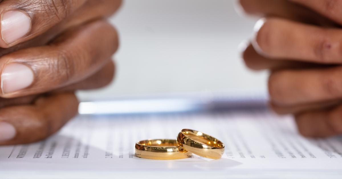 Two hands holding wedding rings above a legal document, symbolising divorce proceedings in the UK.