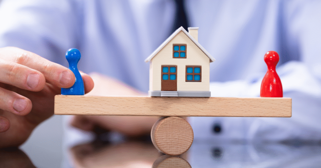 Balance scale with house and figurines representing financial settlement and property division in UK divorce.