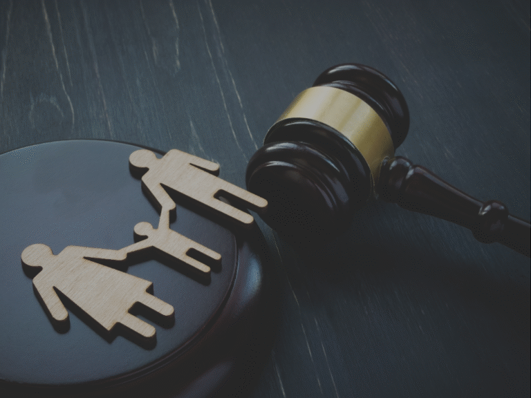 Gavel on dark surface with two wooden cutouts of people beside it, representing family court matters